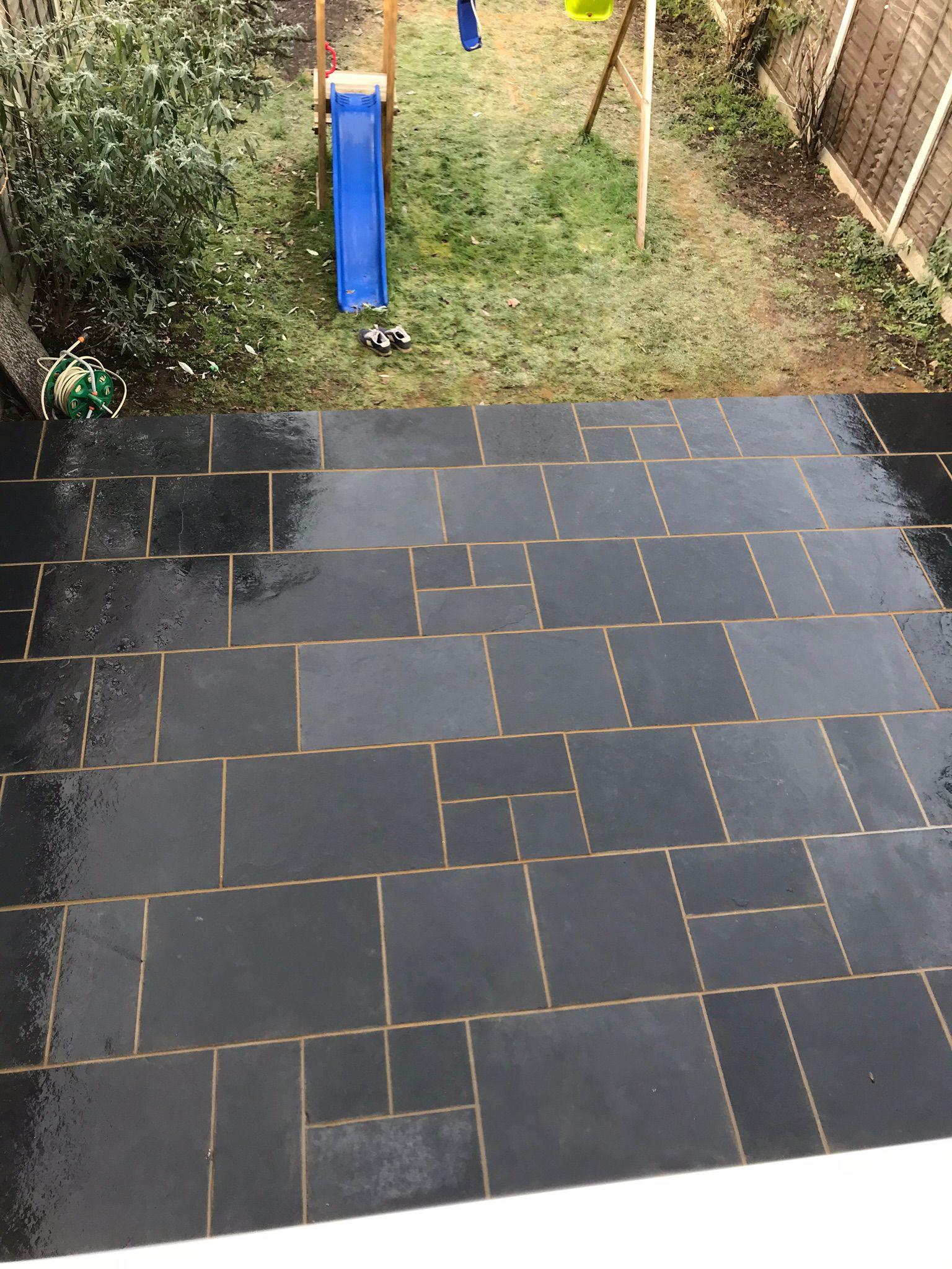 Black slate patio with garden play area and fencing, Surrey