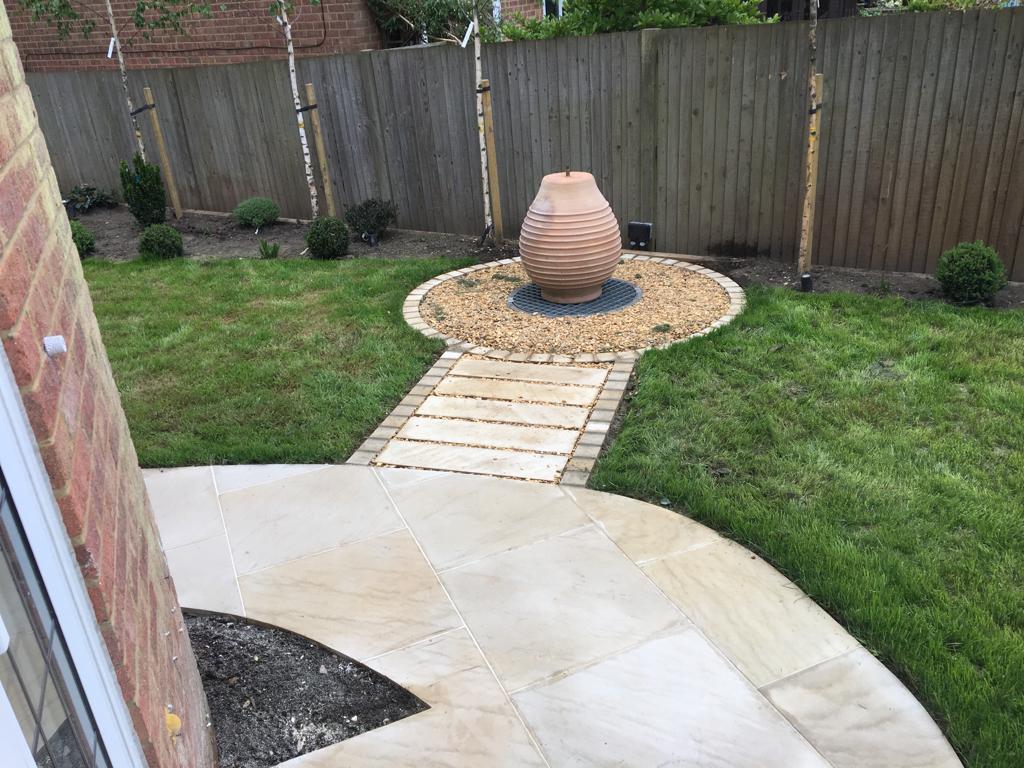 Buff sandstone patio with circular gravel water feature and garden path, Surrey