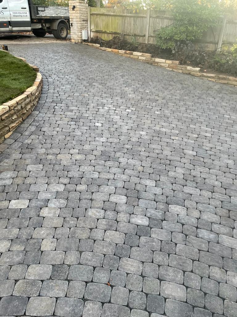 Dark granite sett driveway with curved stone retaining wall and edging, Surrey