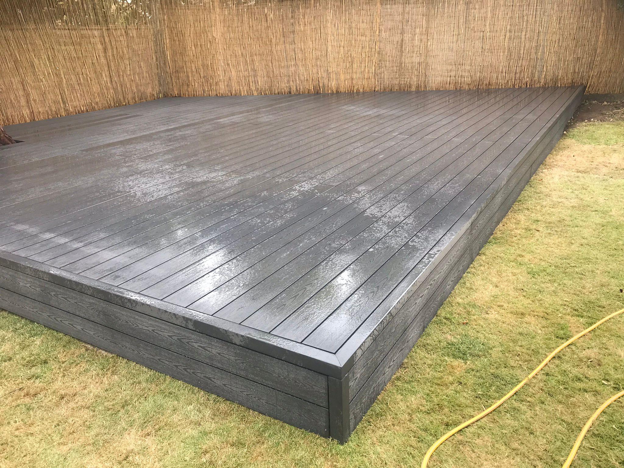 Dark grey composite decking beside bamboo screen, Surrey