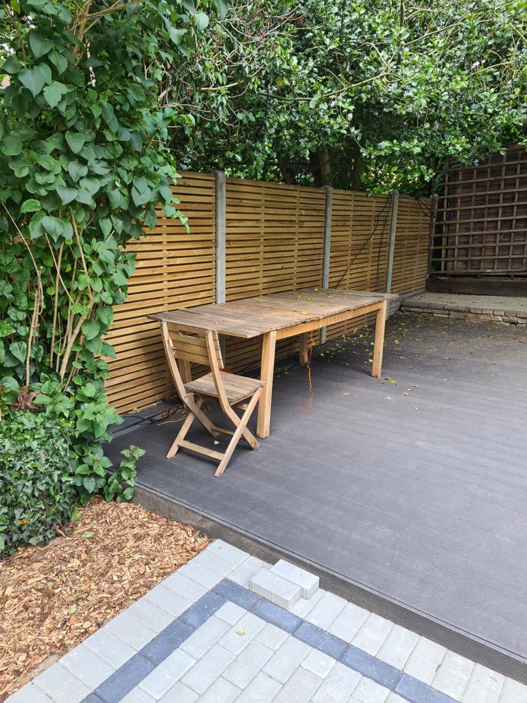 Dark grey composite decking with slatted fence and outdoor dining, Surrey