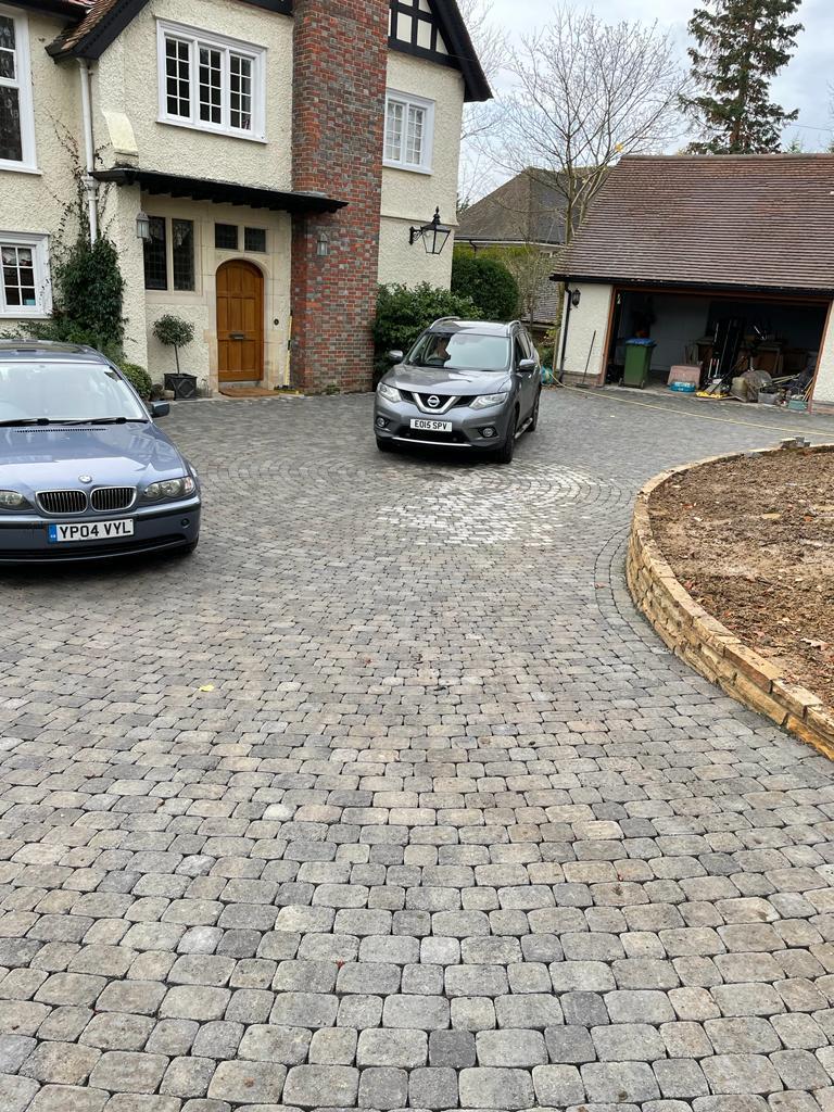 Completed granite cobblestone sett driveway with two cars at detached house, Surrey