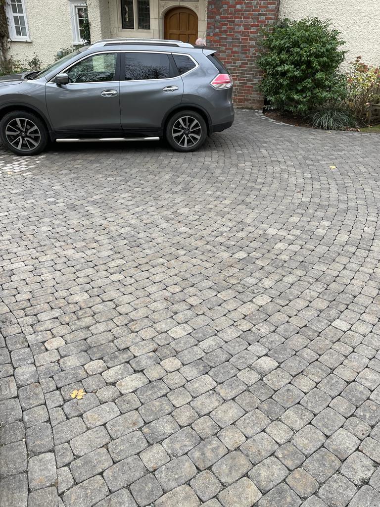 Granite cobblestone sett driveway with parked SUV at detached house, Surrey