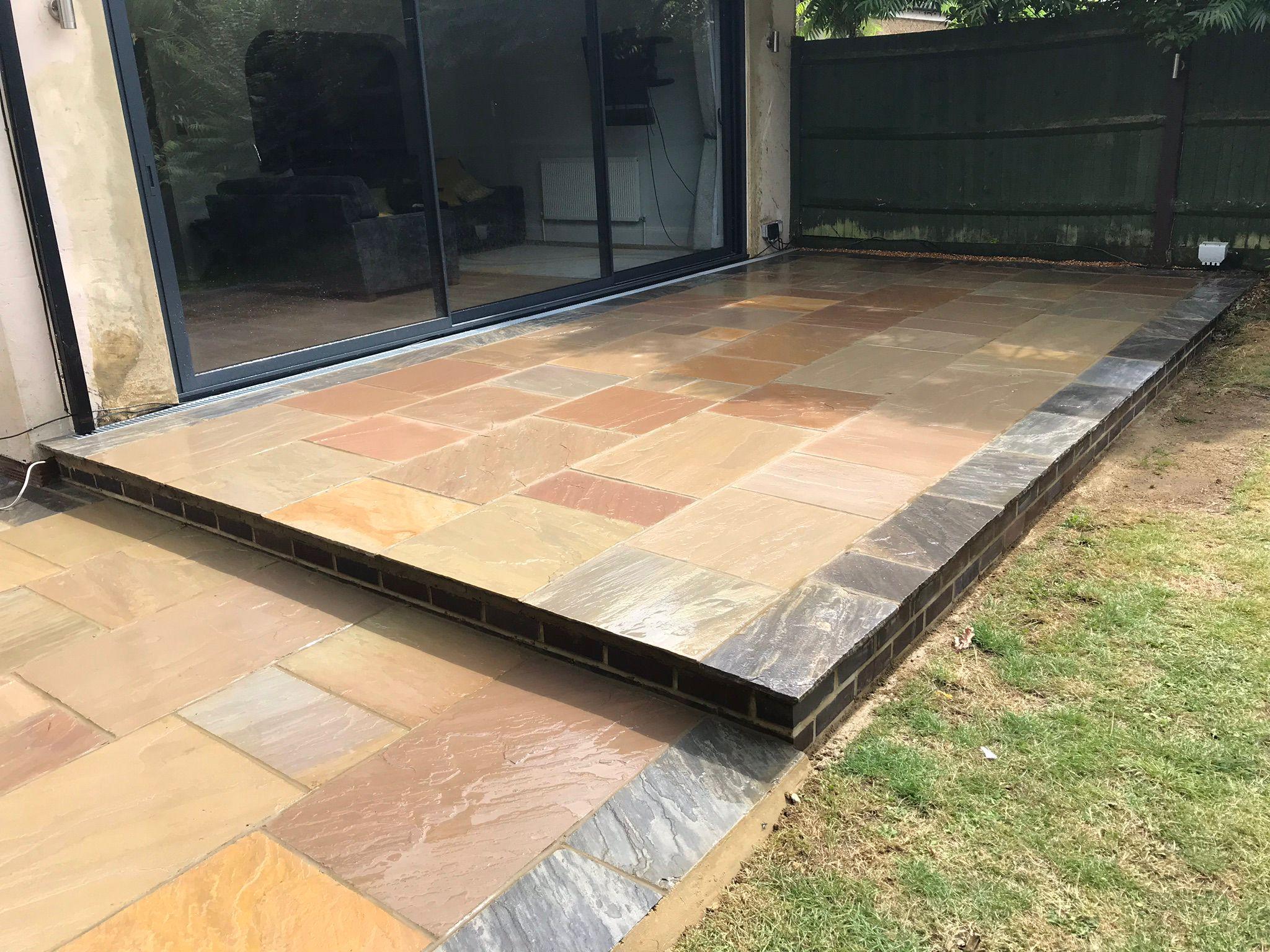 Indian sandstone patio with bi-fold doors and slate edging, Surrey