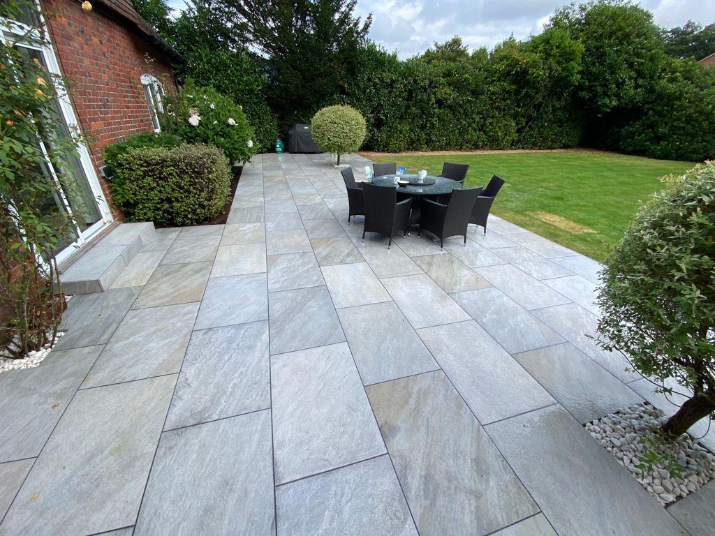 Large grey porcelain patio with dining set and wide lawn, Surrey