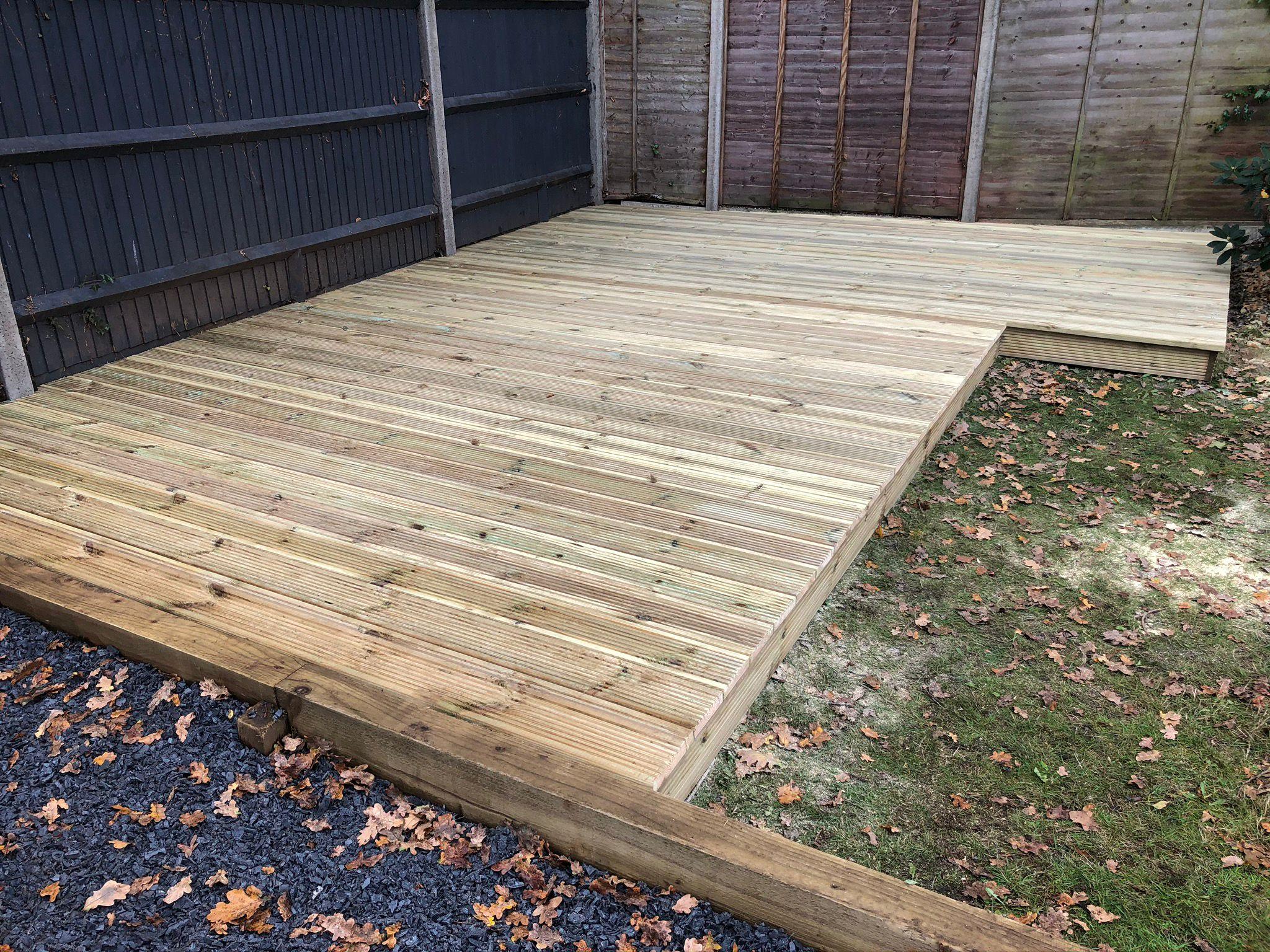 New pressure-treated timber decking with lawn in autumn, Surrey
